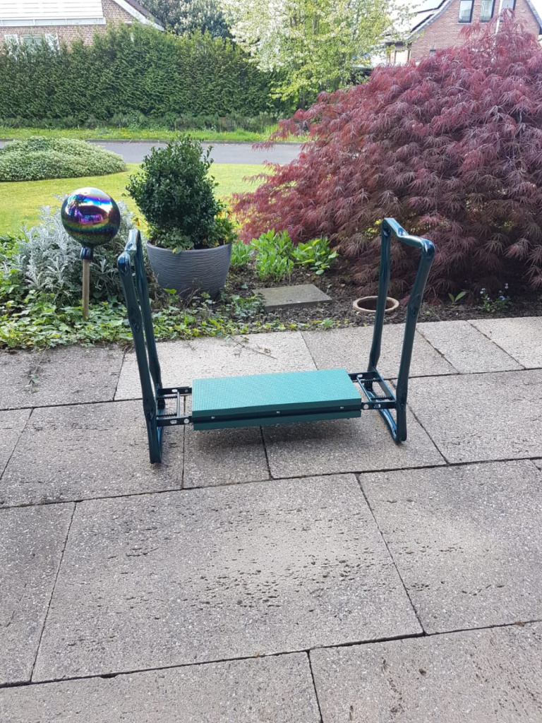 Gartensitz mit ergonomischem Design auf einem gepflasterten Weg in einem Garten.